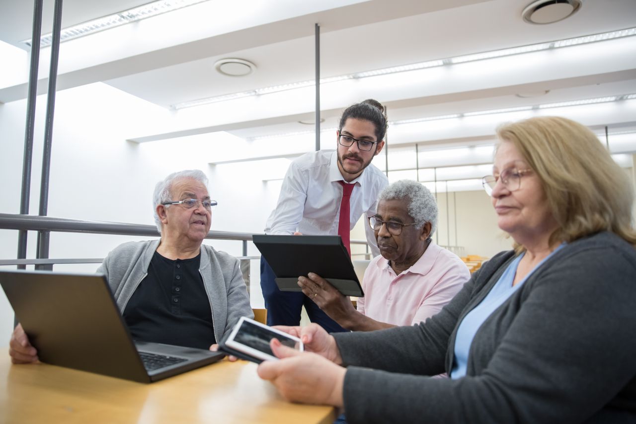 Courses Elderly individuals engage in a digital learning workshop, embracing modern technology in a library setting.